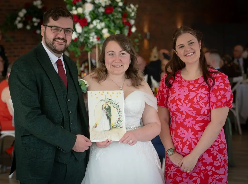 Katie Bowden with the couple and their finished live wedding painting