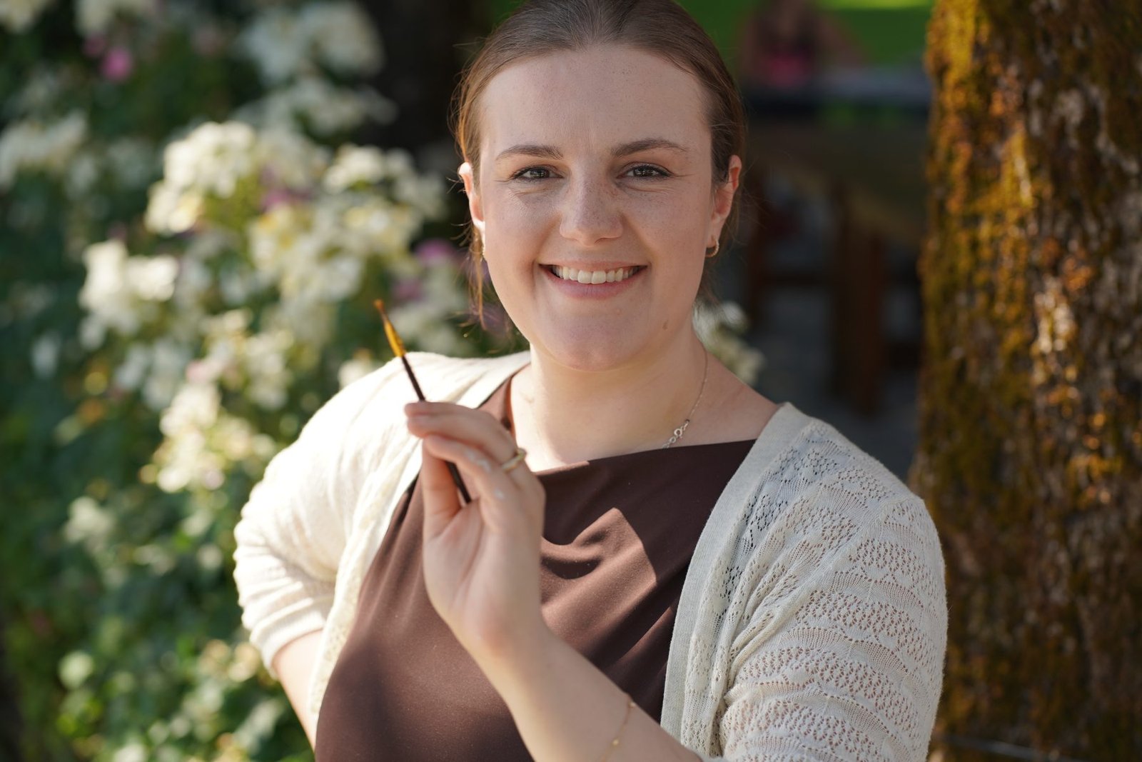 Katie Bowden holding a paintbrush and smiling