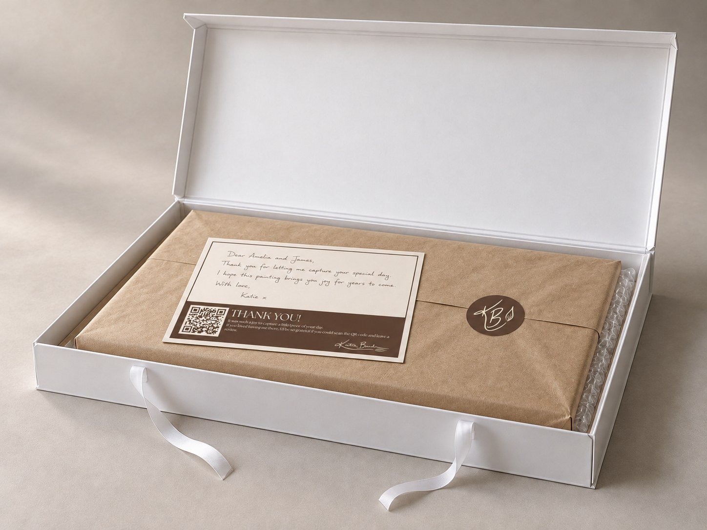 Open keepsake box with a wrapped canvas, handwritten thank-you note and Katie Bowden Art seal